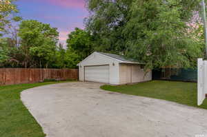 Garage at dusk featuring a yard