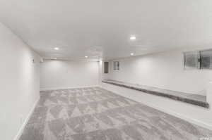 Basement featuring light colored carpet and a textured ceiling