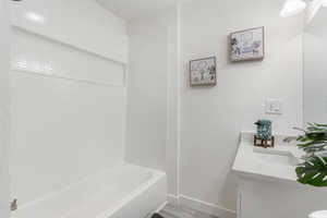 Bathroom with shower / washtub combination, vanity, and hardwood / wood-style flooring