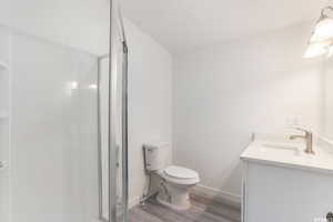 Bathroom with wood-type flooring, vanity, toilet, and an enclosed shower