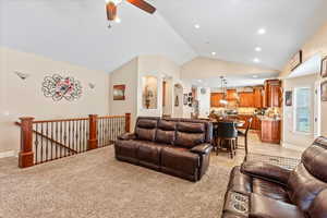 Living room featuring light colored carpet, lofted ceiling, and ceiling fan