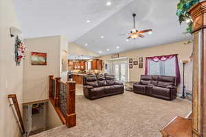 Carpeted living room with lofted ceiling and ceiling fan