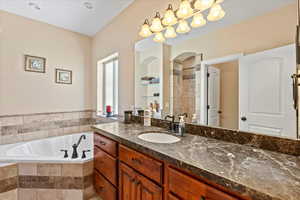 Bathroom featuring tiled bath and vanity