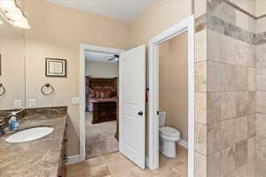 Bathroom with tile patterned flooring, vanity, toilet, and ceiling fan