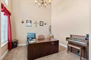 Carpeted office featuring an inviting chandelier