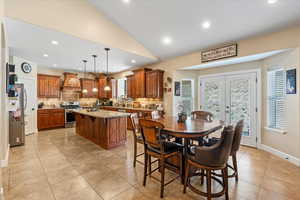 Dining room with french doors, light tile patterned floors, and vaulted ceiling