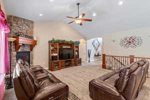 Carpeted living room with lofted ceiling, ceiling fan, and a fireplace