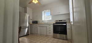 Kitchen with ceiling fan, white cabinets, appliances with stainless steel finishes, and sink