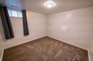 Unfurnished room featuring dark carpet and a textured ceiling