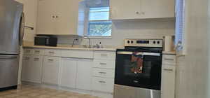 Kitchen featuring appliances with stainless steel finishes, white cabinetry, and sink