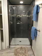 Bathroom with wood-type flooring and a shower with shower door