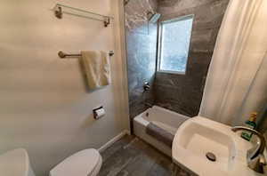 Full bathroom with toilet, shower / tub combo with curtain, and sink