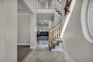 Carpeted entrance foyer with ornamental molding and ceiling fan