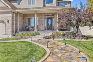 Entrance to property featuring a yard, covered porch, and a garage