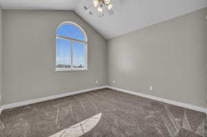 Carpeted spare room featuring ceiling fan and lofted ceiling