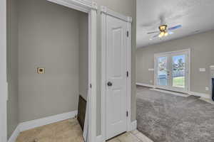 Clothes washing area with a textured ceiling, electric dryer hookup, ceiling fan, french doors, and light carpet