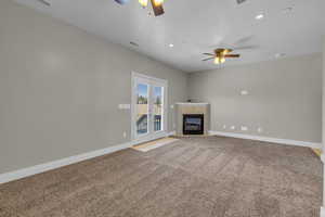 Main floor master suite room featuring a tile fireplace, carpet flooring, and ceiling fan