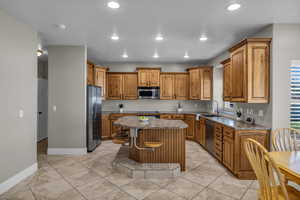 Kitchen featuring a center island, appliances with stainless steel finishes, light tile patterned flooring, and sink