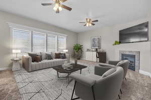 Carpeted living room with a tiled fireplace and ceiling fan (virtually staged)