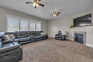 Living room with a fireplace, carpet flooring, and ceiling fan