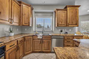 Kitchen featuring dishwasher, sink, and light tile patterned floors