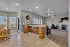 Kitchen with a textured ceiling, a tiled fireplace, ceiling fan, and light colored carpet