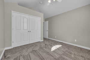 Unfurnished bedroom with a closet, vaulted ceiling, ceiling fan, and light colored carpet