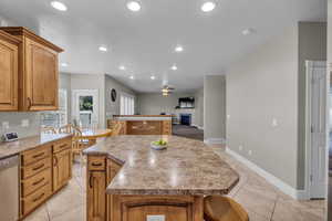 Kitchen featuring ceiling fan, stainless steel dishwasher, light tile patterned floors, and a center island