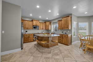 Kitchen featuring appliances with stainless steel finishes, a breakfast bar, light tile patterned floors, and a center island