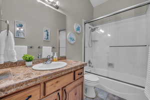 Full bathroom featuring shower / bath combination with glass door, vanity, and toilet