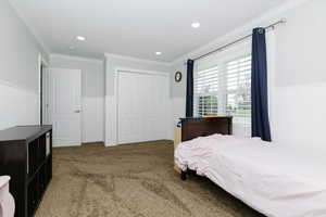 Bedroom with a closet, carpet floors, and crown molding