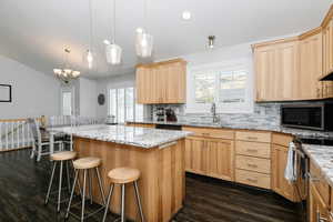 Kitchen with a kitchen breakfast bar, a notable chandelier, a center island, and a wealth of natural light