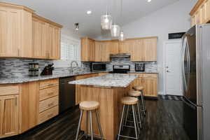 Kitchen with a breakfast bar, stainless steel appliances, lofted ceiling, and tasteful backsplash