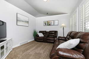 Living room featuring ornamental molding, lofted ceiling, and carpet flooring