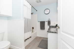 Full bathroom featuring shower / bath combination with curtain, vanity, and toilet