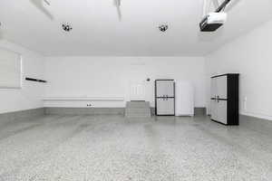 Garage featuring white refrigerator and a garage door opener