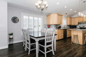 Dining area with lofted ceiling, a chandelier, dark wood-type flooring, and sink