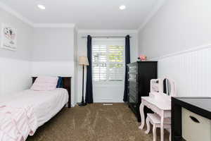 Bedroom with ornamental molding and dark colored carpet