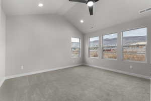 Empty room featuring ceiling fan, light carpet, and vaulted ceiling