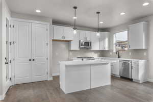 Kitchen featuring white cabinetry, a center island, light hardwood / wood-style floors, pendant lighting, and appliances with stainless steel finishes