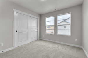 Unfurnished bedroom featuring light colored carpet and a closet