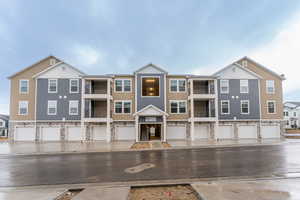 Multi unit property featuring stone siding, an attached garage, and board and batten siding