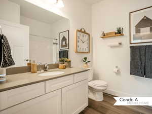 Bathroom with a shower with shower curtain, hardwood / wood-style floors, vanity, and toilet