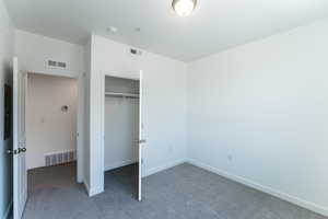 Unfurnished bedroom featuring dark carpet and a closet