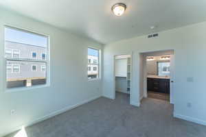 Unfurnished bedroom with dark colored carpet and ensuite bath