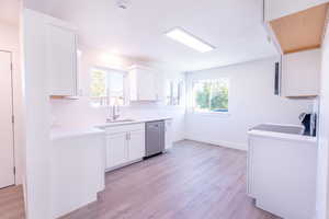 Kitchen featuring white cabinets, light hardwood / wood-style floors, plenty of natural light, and sink