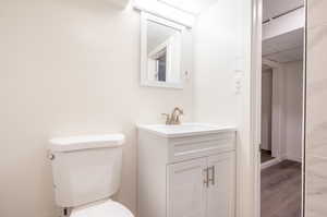 Bathroom featuring wood-type flooring, vanity, and toilet