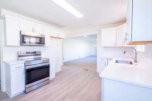 Kitchen featuring light hardwood / wood-style flooring, appliances with stainless steel finishes, sink, and white cabinetry