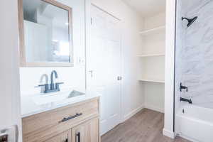 Bathroom featuring wood-type flooring, vanity, and tiled shower / bath combo