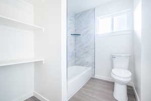 Bathroom with hardwood / wood-style floors, toilet, and tiled shower / bath